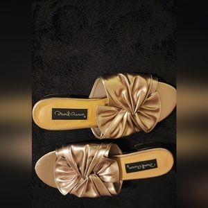 A gold pair of casual slides with a knot.